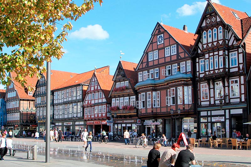 Ein Mann hält in einer Bar einen Vortrag über Wasserstoff, Publikum hört aufmerksam zu.
