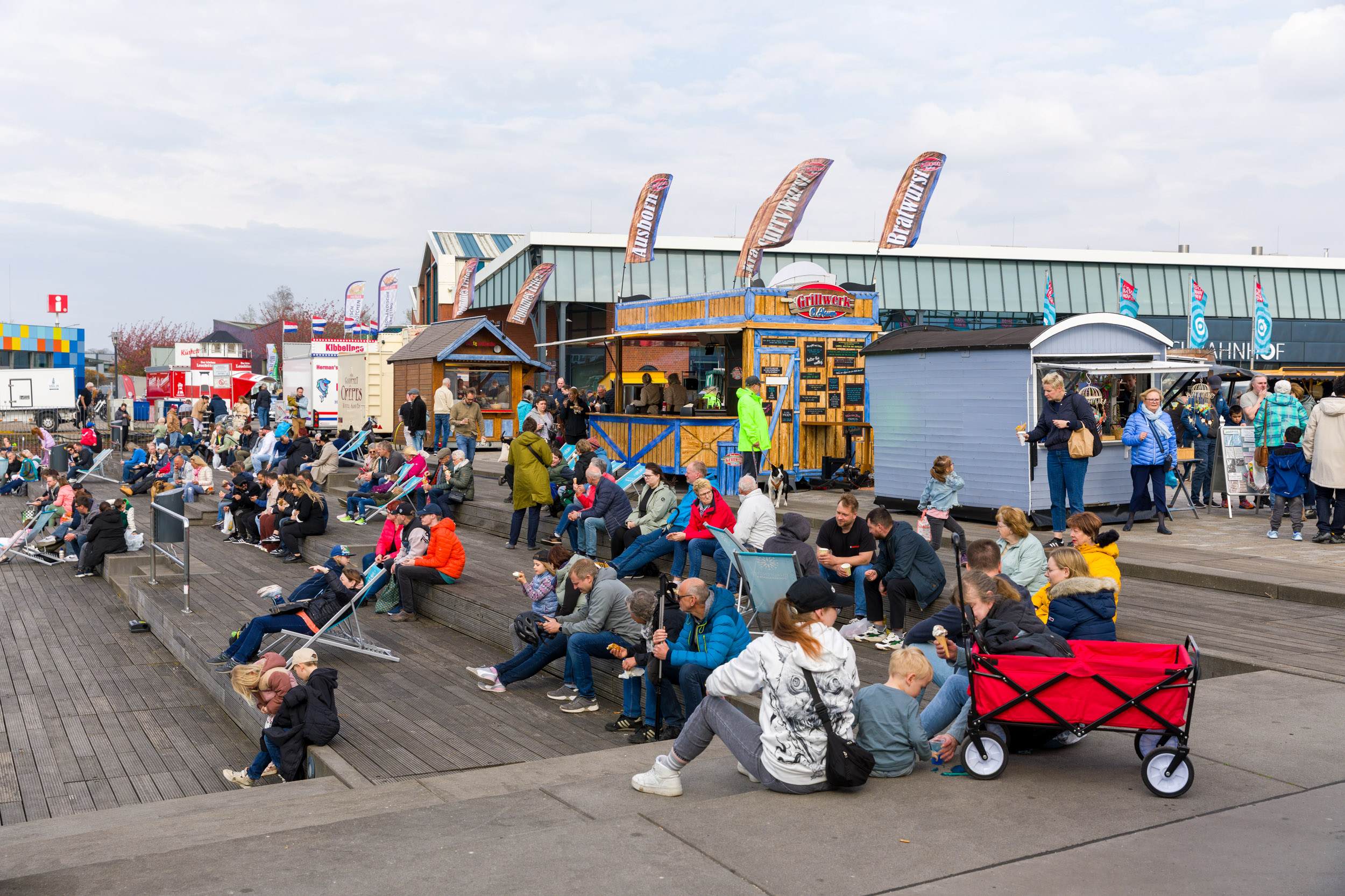 Menschen sitzen gemütlich im Schaufenster Fischereihafen und schauen aufs Wasser