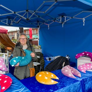Eine Verkäuferin präsentiert ihre Ware auf dem Bauernmarkt im Schaufenster Fischereihafen