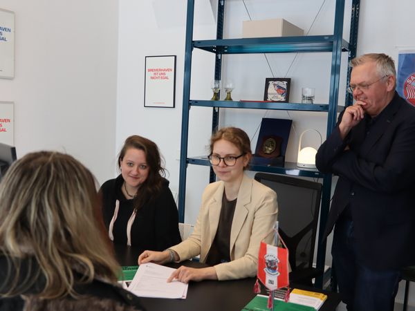 Bürgermeister Torsten Neuhoff eröffnet gemeinsam mit Marie Garms und Benthe Stolz von der Erlebnis Bremerhaven das Beratungsbüro zum Stadtjubiläum.