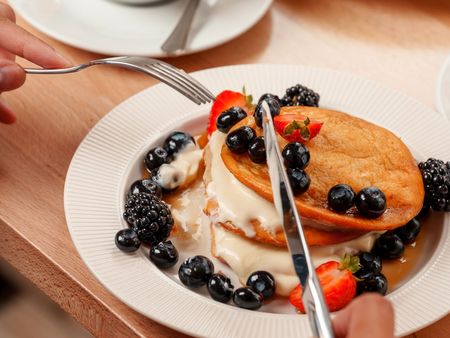 Kaffee mit Herz im Schaum, Pancakes mit Blaubeeren, Erdbeeren und Soße im Café Lieblingsplatz