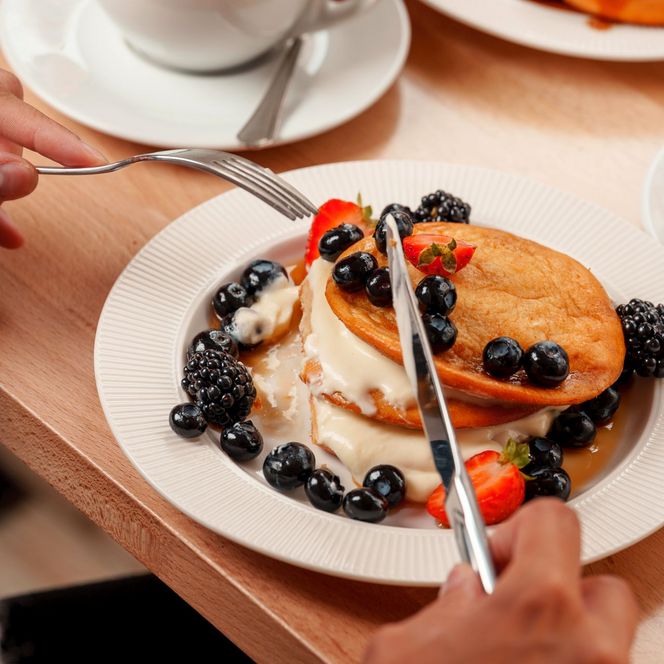 Kaffee mit Herz im Schaum, Pancakes mit Blaubeeren, Erdbeeren und Soße im Café Lieblingsplatz