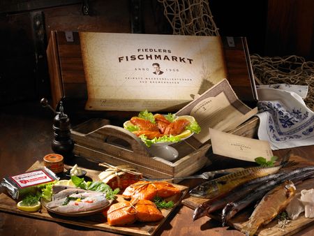 Geschenkbox mit geräuchertem Fisch, frischen Meeresdelikatessen und maritimer Dekoration.