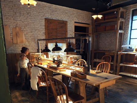 Historische Schneiderei mit Nähmaschinen, Holzmöbeln und Figuren in Arbeitskleidung.