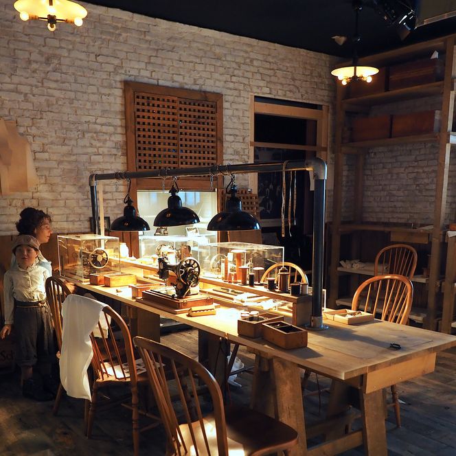 Historische Schneiderei mit Nähmaschinen, Holzmöbeln und Figuren in Arbeitskleidung.