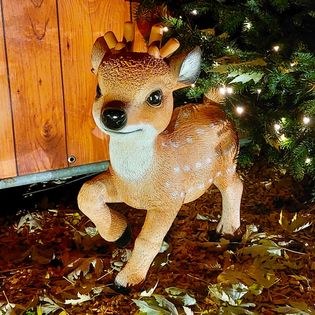 EIn kleines Rentier steht unter einem Weihnachtsbaum auf dem Weihnachtsmarkt