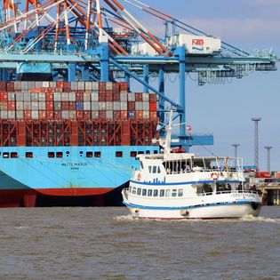 MS Geestemünde bei der Rundfahrt auf der Weser mit riesigem Containerschiff im Hintergrund