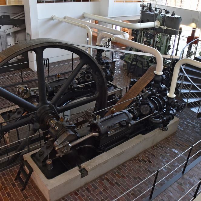 Historische Kältemaschine mit Schwungrad und Rohrleitungen im Industrieraum des Museums.