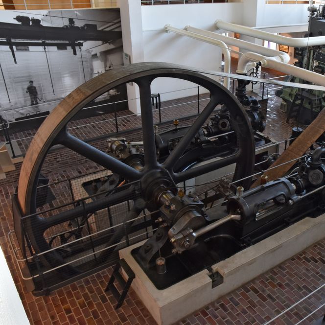 Historische Kältemaschine mit Schwungrad und Rohrleitungen im Industrieraum des Museums.