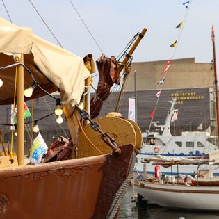 Blick über den Bug der Margrit und Traditionsschiffe auf das Deutsche Auswandererhaus