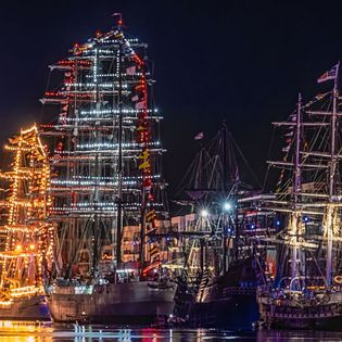 Der Hafen bei Nacht mit beleuchteten Segelschiffen
