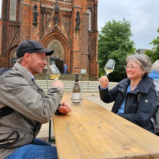 Ein Pärchen stösst mit Weingläsern vor der Großen Kirche an.