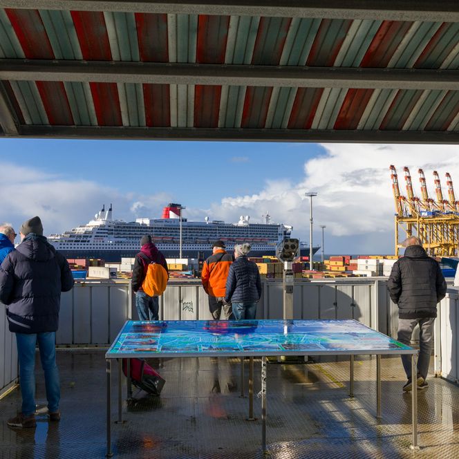 Menschen stehen auf dem Container-Aussichtsturm und beobachten das Treiben in den Überseehäfen