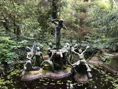 Bronzeskulpturengruppe "Die Geburt der Venus" mit neun Figuren in einem Teich, umgeben von dichtem grünen Wald.