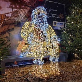 Großer, beleuchteter Weihnachtsmann in weiß auf dem Weihnachtsmarkt