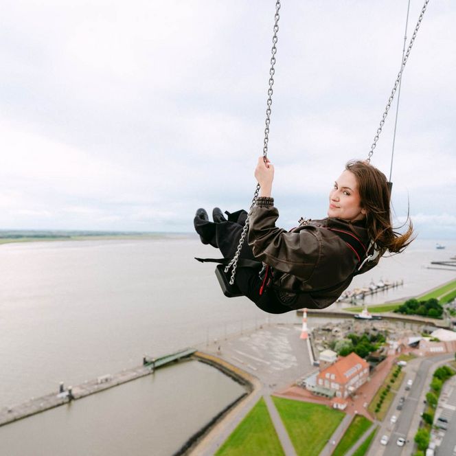Eine Frau schaukelt in 86 m Höhe an einer Aussichtsplattform über Bremerhaven