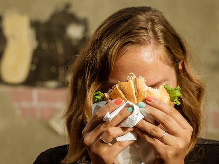 Eine Frau hält ein Fischbrötchen vor ihr Gesicht