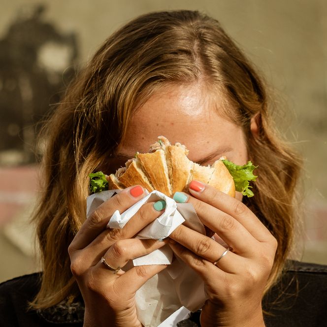 Eine Frau hält ein Fischbrötchen vor ihr Gesicht