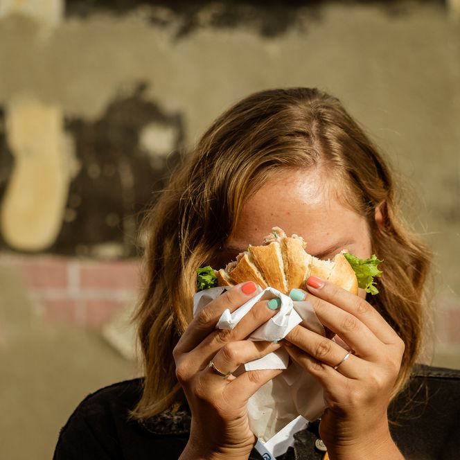 Eine Frau hält ein Fischbrötchen vor ihr Gesicht