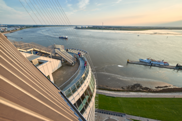 Blick von der Aussichtsplattform SAiL City auf die Weser mit vorbeifahrenden Schiffen bei Sonnenlicht.