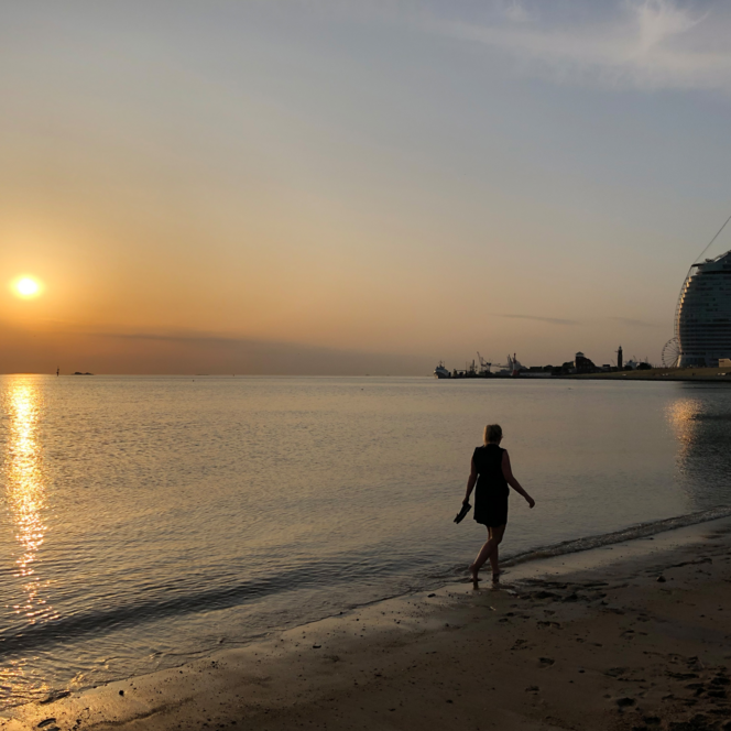 Frau spaziert am Weser-Strandbad in Bremerhaven bei Sonnenuntergang.