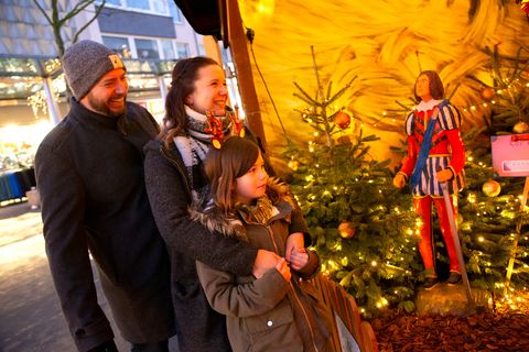 Eine Familie vor einer Märchenhütte auf dem Weihnachtsmarkt