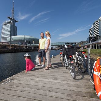 Familie macht mit ihren Rädern Pause auf dem Holzsteg in den Havenwelten in Bremerhaven