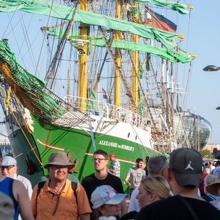 Menschen schlendern an den Kajen entlang. Im Hintergrund die Alexander von Humboldt II