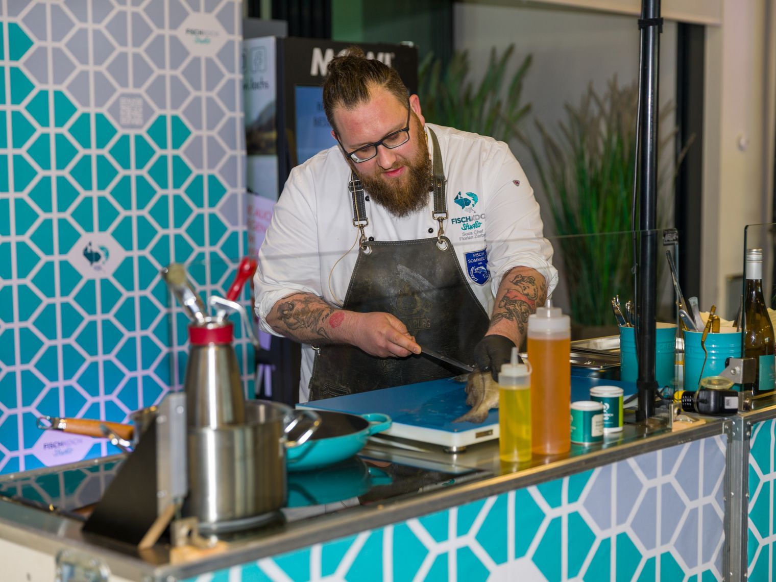 Ein Koch filitiert einen Fisch vor Zuschauern.