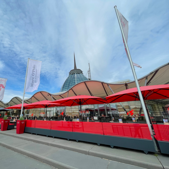 Rote Sonnenschirme auf der Außenterrasse des Restaurants Gosch Sylt am Hafen in Bremerhaven.