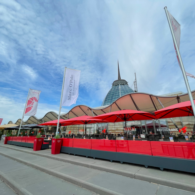 Rote Sonnenschirme auf der Außenterrasse des Restaurants Gosch Sylt am Hafen in Bremerhaven.
