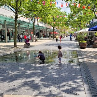 Kinder spielen an einem Brunnen