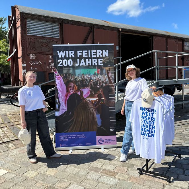 Zwei Frauen vor einem Banner mit der Aufschrift "Wir feiern 200 Jahre"