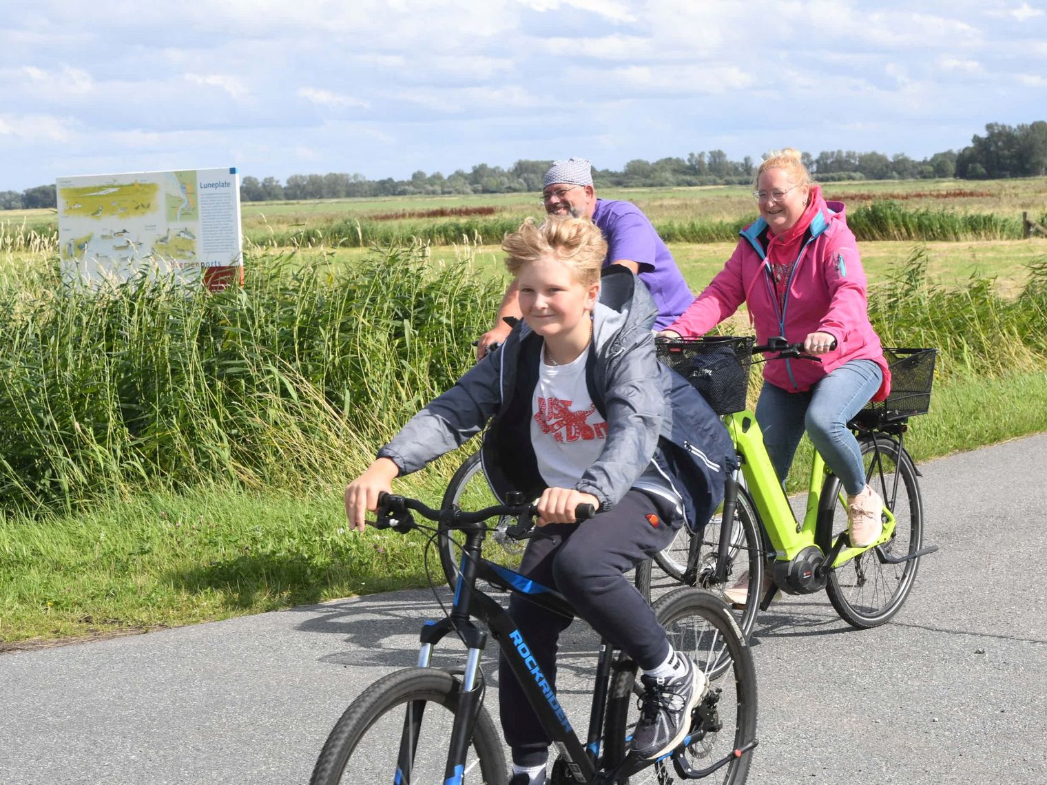 Familie fährt mit Fahrrädern durch das Naturschutzgebiet "Luneplate"