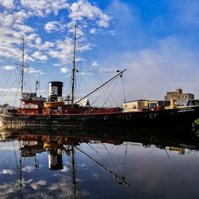 Der Hochseeschlepper Seefalke liegt im Hafen von Bremerhaven, im klaren Wasser und Morgenlicht.