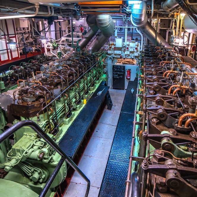 Blick in den Maschinenraum des Museumsschiffs Gera mit sichtbaren Motoren und Leitungen.