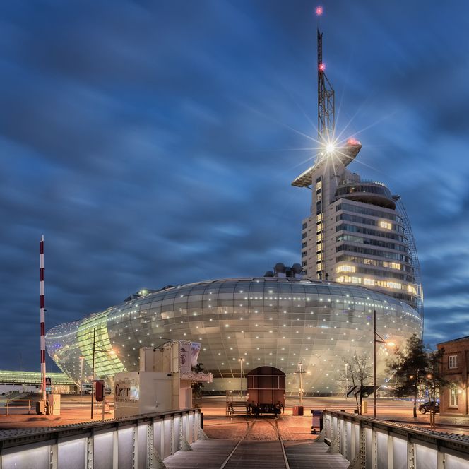 Beleuchtetes Klimahaus Bremerhaven bei Abenddämmerung mit modernem Glasbau und Himmel im Hintergrund