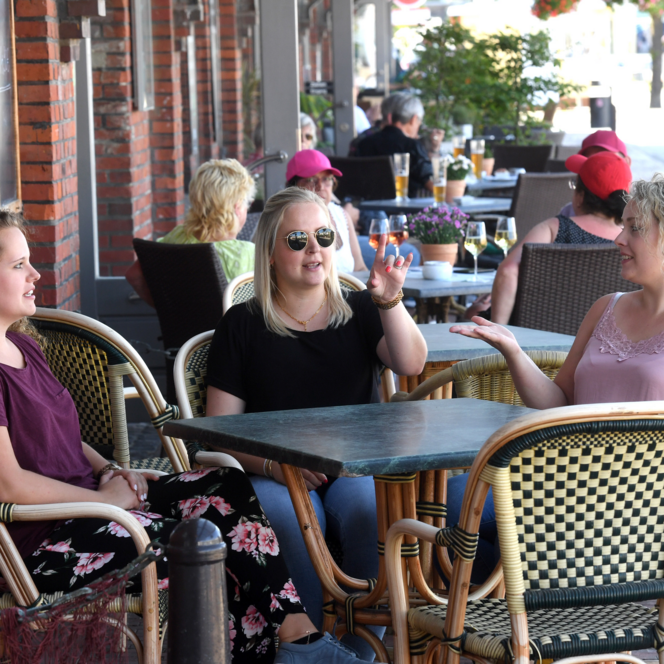 Drei Frauen sitzen plaudernd an einem Café-Tisch im Schaufenster Fischereihafen Bremerhaven.