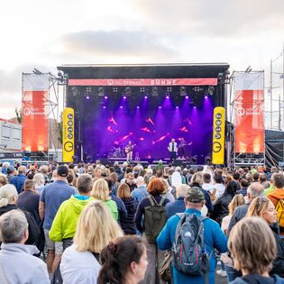Menschen vor einer großen Bühne im Freien
