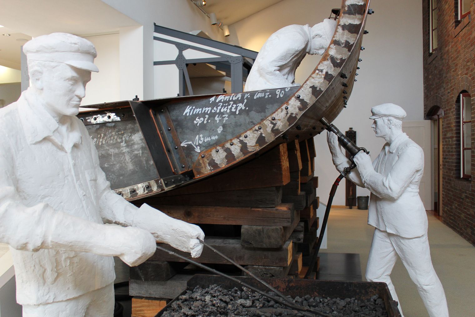 Zwei Puppen stehen an einer Schiffswand und schrauben Bolzen rein. Szene aus einem Museum