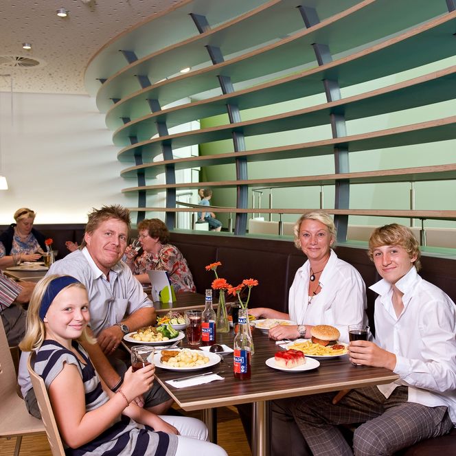 Eine Familie sitzt im modernen Restaurant des Klimahauses Bremerhaven und isst gemeinsam zu Mittag.