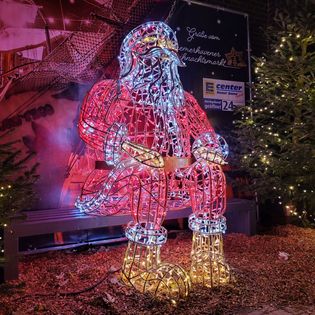 Großer, beleuchteter Weihnachtsmann in rot auf dem Weihnachtsmarkt