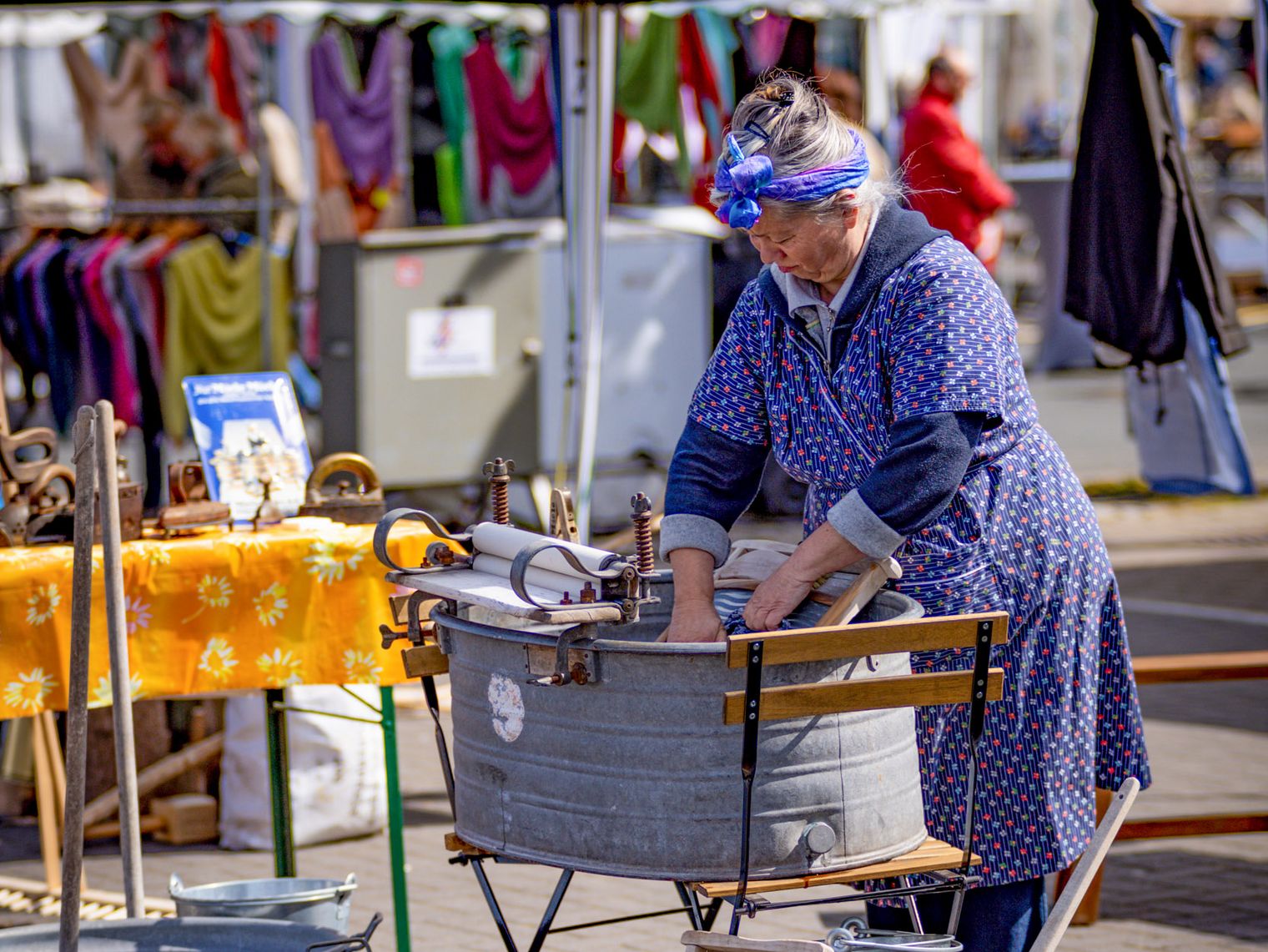 Eine ältere Frau in traditioneller Kleidung präsentiert altes Handwerk