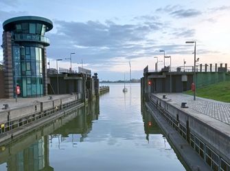 Blick durch die offene Schleuse Neuer Hafen hinaus auf die Weser, von wo ein Segelboot einläuft