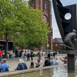 Am Brunnen in der Fußgängerzone sitzen und der Musik auf der Bühne neben der Großen Kirche lauschen.