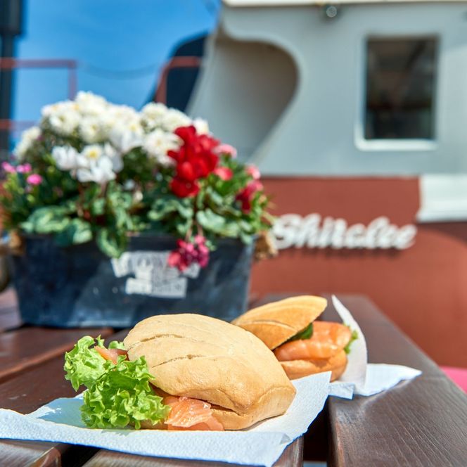 Zwei Fischbrötchen und Blumenarrangement auf dem Tisch an Bord eines Kutters