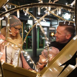 Familie vor großem Lichtobjekt auf dem Weihnachtsmarkt