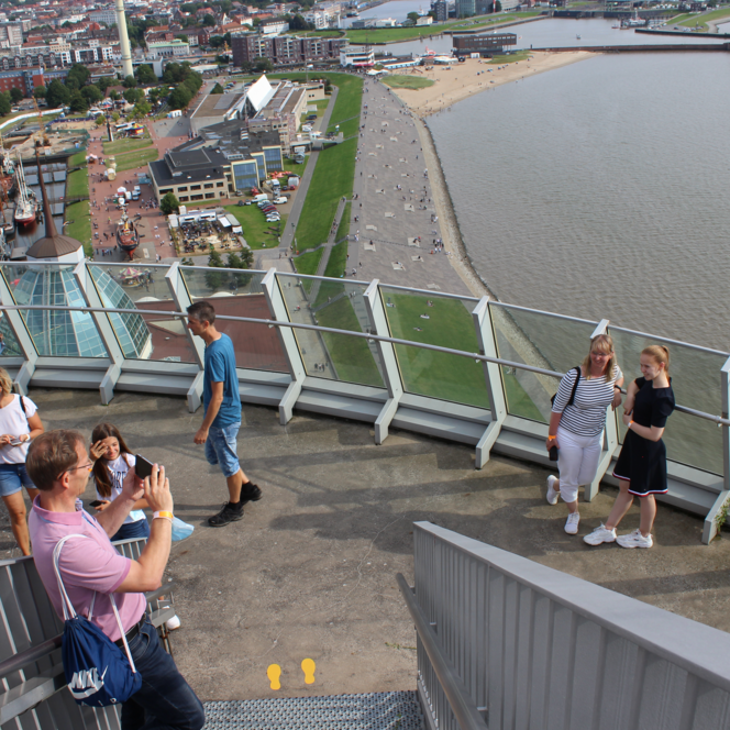 Menschen auf der Aussichtsplattform Sail City blicken über Bremerhaven und das Weser-Strandbad.