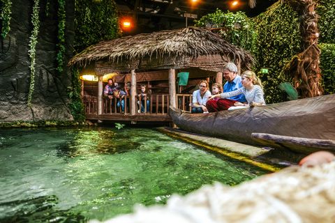 Eine Familie sitzt an einem Strand und schaut auf das Wasser. Nachgebaute Szene im Klimahaus Bremerhaven
