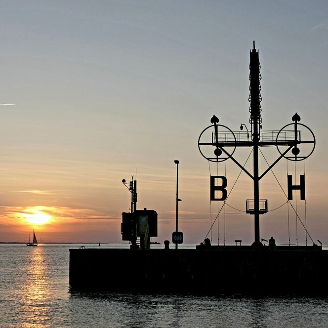 Sonnenuntergang über der Weser in Bremerhaven und über dem Semaphor auf der Kaimauer